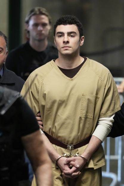 Luigi Mangione, handcuffed and wearing a tan uniform, is escorted into Manhattan state court.