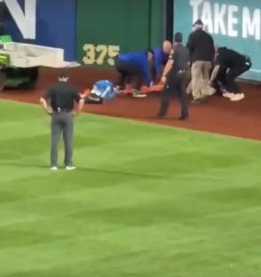 Injured baseball fan being attended to on the field.