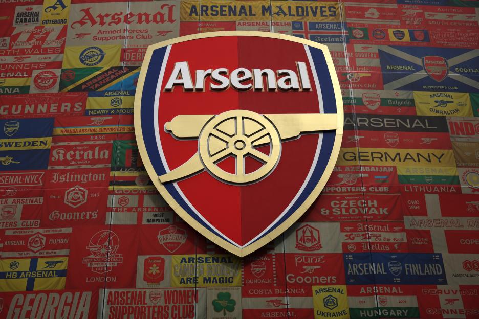 Arsenal badge on a wall covered with flags of Arsenal supporters' clubs from around the world.