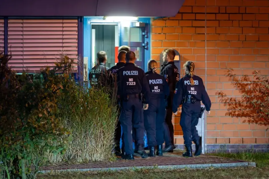 German police officers gathered outside a building at night.