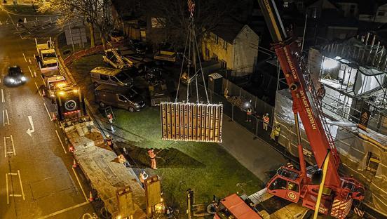 Nighttime aerial view of a crane lifting a section of a mural during removal.
