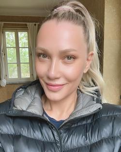 a woman wearing a black jacket is smiling in front of a window