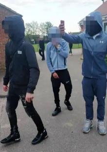 Three hooded teens, one taking a selfie.