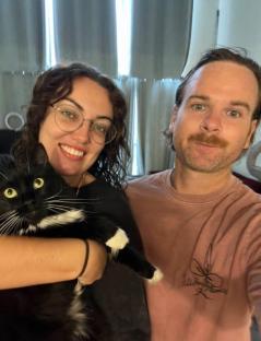 Couple holding a tuxedo cat.