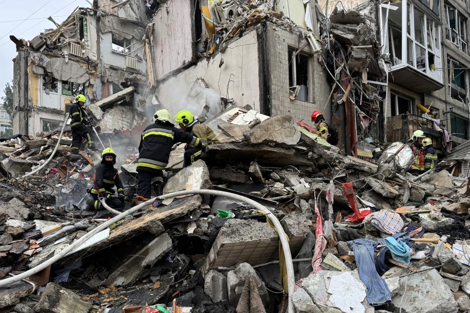 Emergency workers amidst rubble from a bombed residential building.