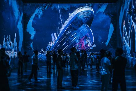 People viewing a large-scale projection of the Titanic sinking.