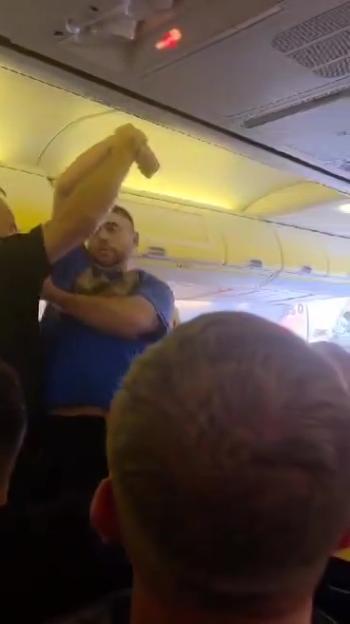 Police officers removing a disruptive passenger from a plane.