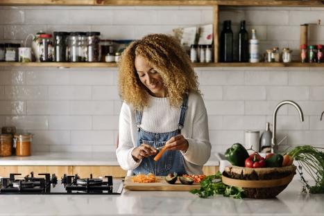 Smiling woman peeling carrots in her kitchen.