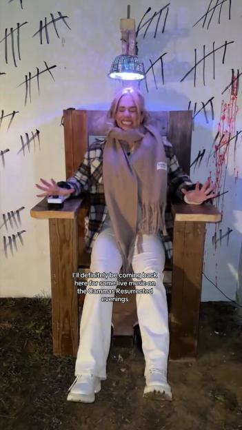 Woman sitting in an electric chair with tally marks on the wall behind her.