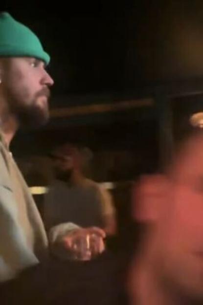 Justin Bieber wearing a green beanie and a beard in a dimly lit setting.