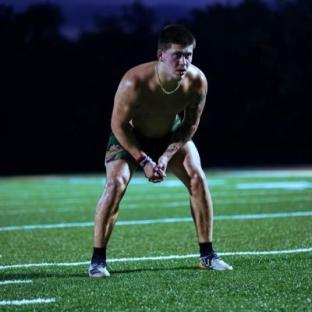 Man in athletic shorts crouching on a football field.