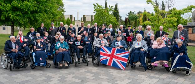 Group of veterans in wheelchairs at a VE Day commemoration.