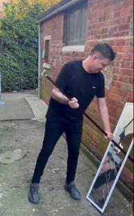 Man smashing a mirror with a cane.