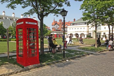 Red telephone booth in a park-like setting in Thames Town, China.