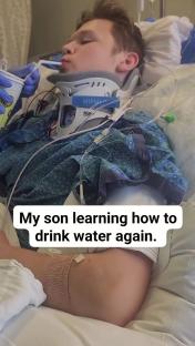 Teenage boy in a neck brace drinking water with a straw in a hospital bed.