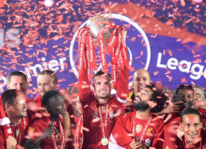 Jordan Henderson holds the Premier League trophy aloft with Mohamed Salah and other Liverpool F.C. players.