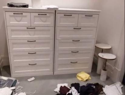 Two white dressers and clothes on the floor.