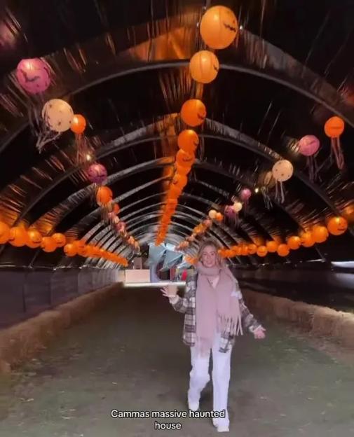 A woman walking through an archway decorated with Halloween lanterns.