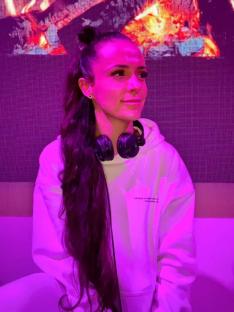 Woman with long hair wearing headphones and a white hoodie.