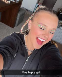 A very happy girl with glitter makeup and braided hair.