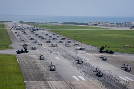 Aerial view of military aircraft and vehicles on a runway during an elephant walk exercise.