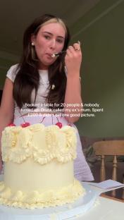 Woman eating cake in front of a large decorated cake.