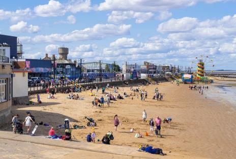 Cleethorpes beach with fun fair and many people enjoying the day.