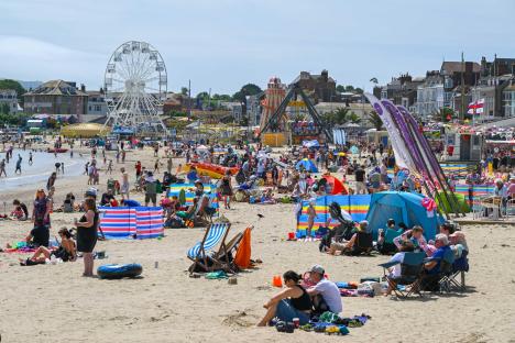 Busy beach with families enjoying the sun and seaside attractions.
