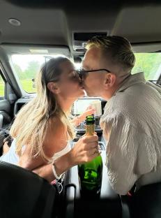 Couple kissing in a car with a bottle of champagne.
