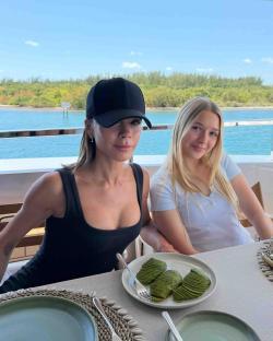 Victoria Beckham and Harper Beckham sitting at a table outdoors.