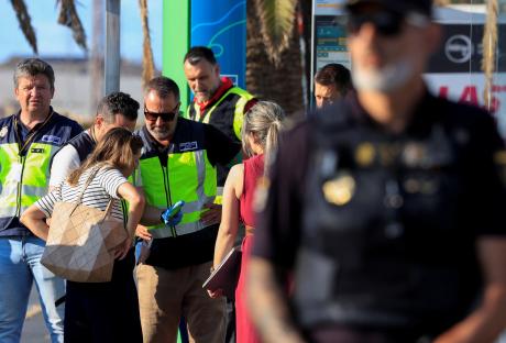 Spanish National Police officers examining a mobile phone at an airport.
