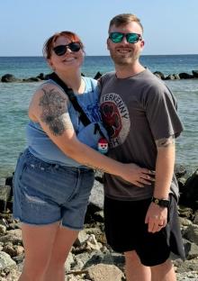 Couple posing for a photo by the ocean.