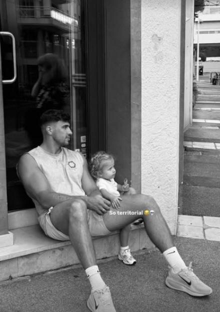 Black and white photo of a man sitting on a step with a toddler.