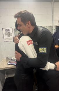 Two men in suits embracing.