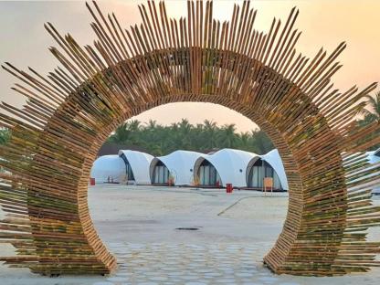 Bamboo archway framing Bangaram Island resort bungalows.