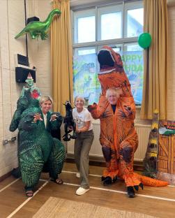Three people in inflatable dinosaur costumes at a children's party.