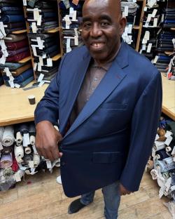Man in a navy blazer standing in a fabric store.