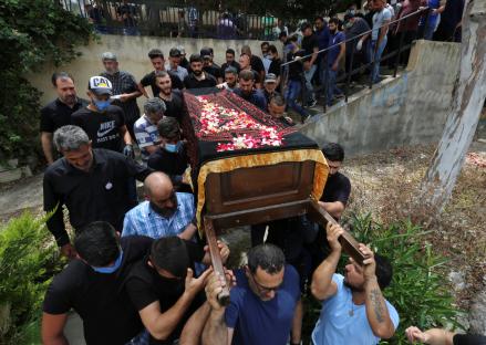 Mourners carry a coffin adorned with flowers at a funeral.