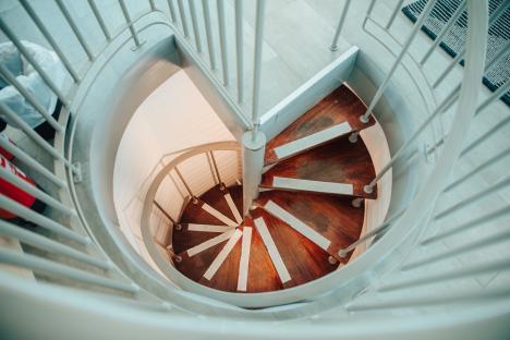 Spiral staircase with wooden steps and light-grey railings.