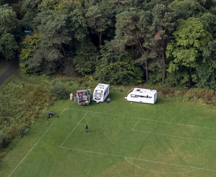 Aerial view of caravans parked on a football pitch.