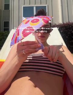 Person sunbathing with a grapefruit-print parasol.