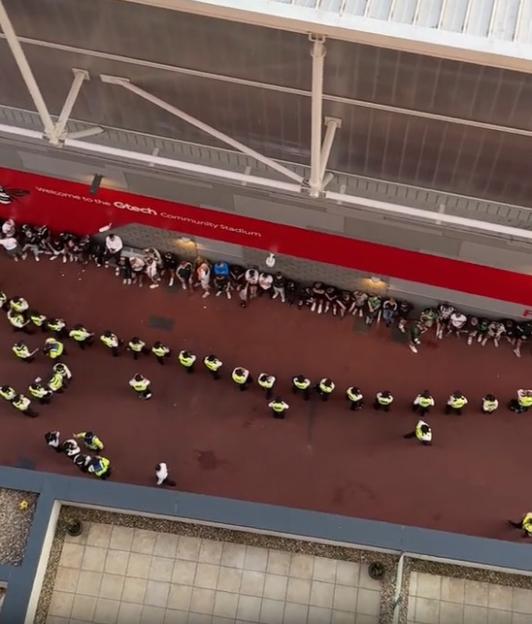 Aerial view of police officers and spectators outside the Gtech Community Stadium.