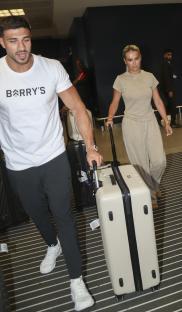 Molly Mae and Tommy Fury arriving at an airport with luggage.