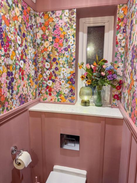 Pink bathroom with floral wallpaper, new sink vanity unit, and flowers.