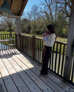 Woman holding a baby on a deck overlooking a waterway.