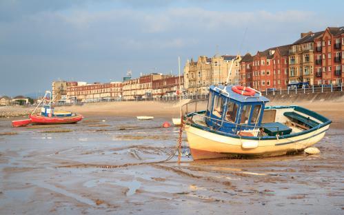 Boats moored on a muddy beach in Morecambe, Lancashire, England.