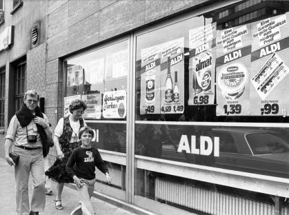 Black and white photo of pedestrians walking past an Aldi store in Frankfurt, Germany in 1980.