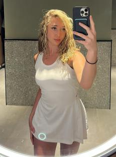 Woman with blonde hair and black top holding a black purse.