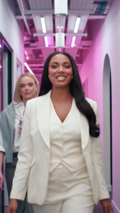 Woman in white suit walking down a hallway.