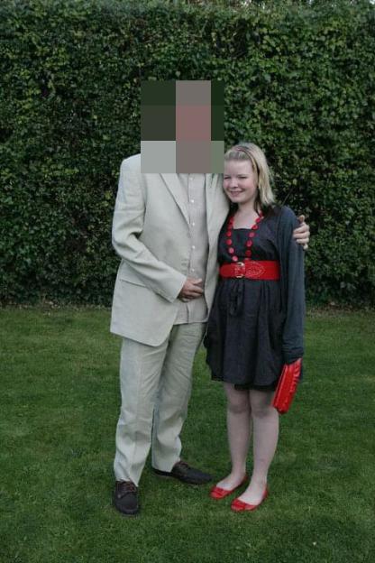 A man and a young woman stand together on a lawn.